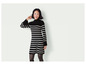 Une femme porte une robe pull à rayures noires et blanches.