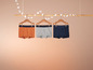 Trois paires de boxers de couleurs différentes, suspendus à un porte-manteaux en bois.