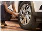 Un homme utilise une clé dynamométrique pour serrer une roue de voiture.
