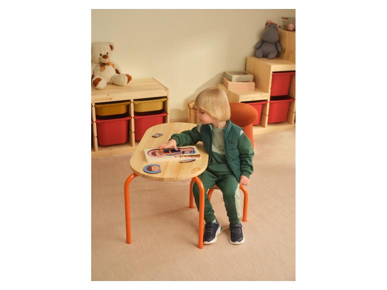 Un enfant joue avec un puzzle en bois du corps humain LUPILU® sur une petite table.