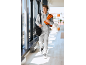 Homme en survêtement gris avec sac de sport noir et serviette orange.