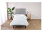 Une couette blanche sur un cadre de lit gris dans une chambre à coucher.