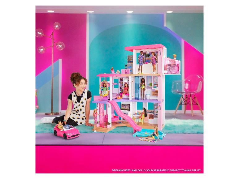 Fille jouant avec une maison de rêve Barbie et des poupées Barbie.