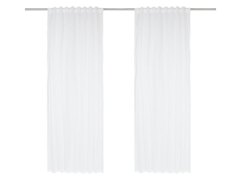 Des rideaux blancs sur une tringle en métal.