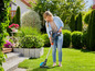 Une femme utilise une débroussailleuse sans fil dans son jardin.