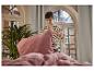 Femme arrangeant un lit avec des draps et des oreillers roses.