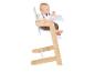 Bébé assis dans une chaise haute en bois et blanche avec plateau.