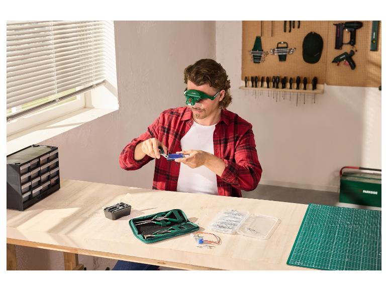 Homme travaillant sur un établi avec des lunettes loupe LED PARKSIDE®.