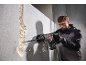 Homme avec des lunettes de sécurité utilisant un marteau perforateur pour casser un mur.