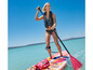 Une femme pagaye sur un paddleboard rose avec une pagaie rouge.