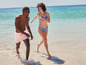 Un couple en maillot de bain se promène sur la plage.