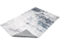 Tapis abstrait gris et blanc avec motif texturé, montrant son envers