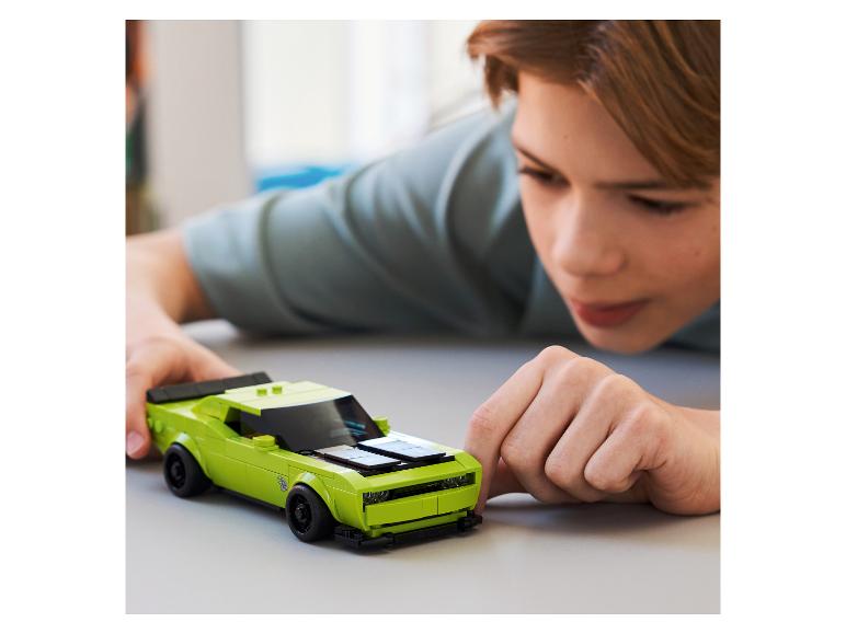 Un enfant joue avec une voiture de sport verte en briques de construction.