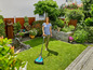Une femme tond la pelouse dans son jardin avec une tondeuse à gazon Bosch.