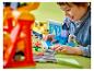 Un enfant souriant joue avec un train LEGO Duplo et une station de lavage.