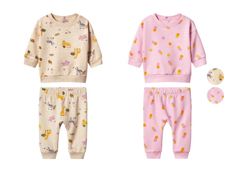 Deux ensembles de vêtements pour bébé, un beige à motif animaux de la jungle et un rose à pois colorés.