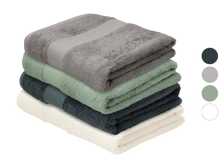Pile de quatre serviettes pliées en gris, vert, bleu foncé et crème avec des échantillons de couleur.