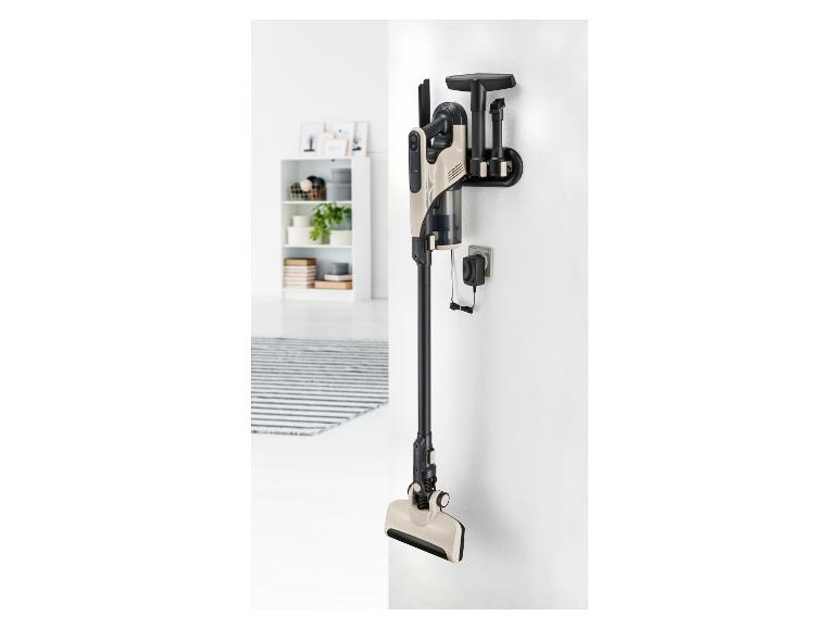 Un aspirateur avec différents accessoires accroché au mur.