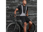 Un homme en tenue de vélo avec un short et un t-shirt, appuyé contre un vélo de route.