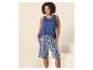 Femme souriante en débardeur bleu et short à motifs bleus et blancs.