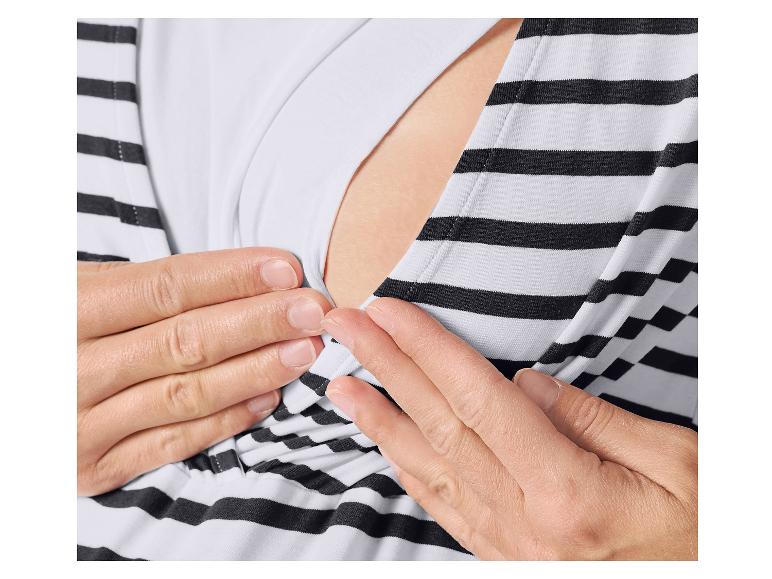 Gros plan des mains d'une femme ajustant un haut de maternité et d'allaitement rayé.