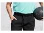 Un homme portant un pantalon de jogging noir et un t-shirt bleu clair, tenant un ballon de basket-ball.