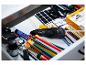 Un tiroir rempli de fournitures d'art et d'artisanat, y compris un pistolet à colle, des tubes de peinture et des crayons.