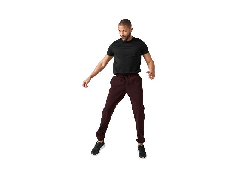 Un homme en t-shirt noir et pantalon marron saute.