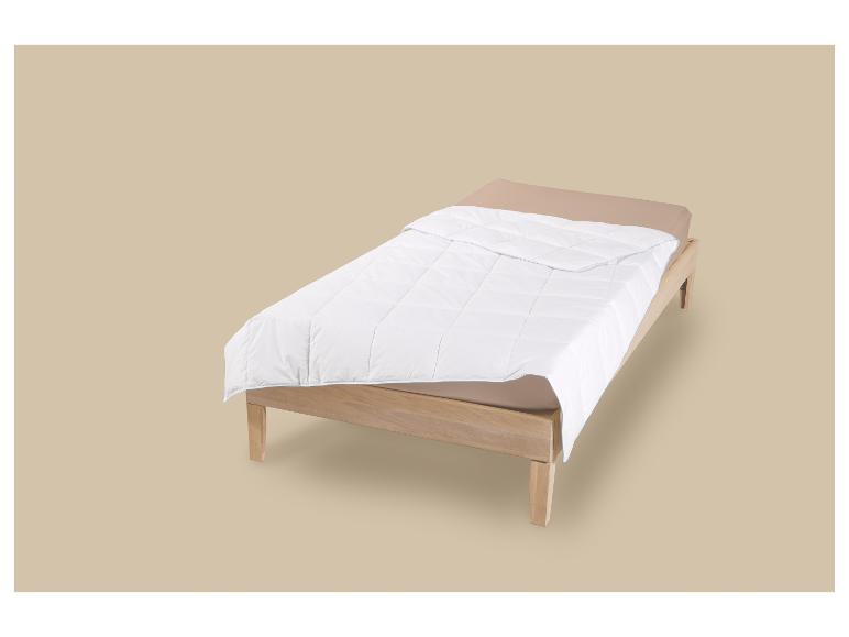 Lit simple en bois avec matelas beige et couette blanche.