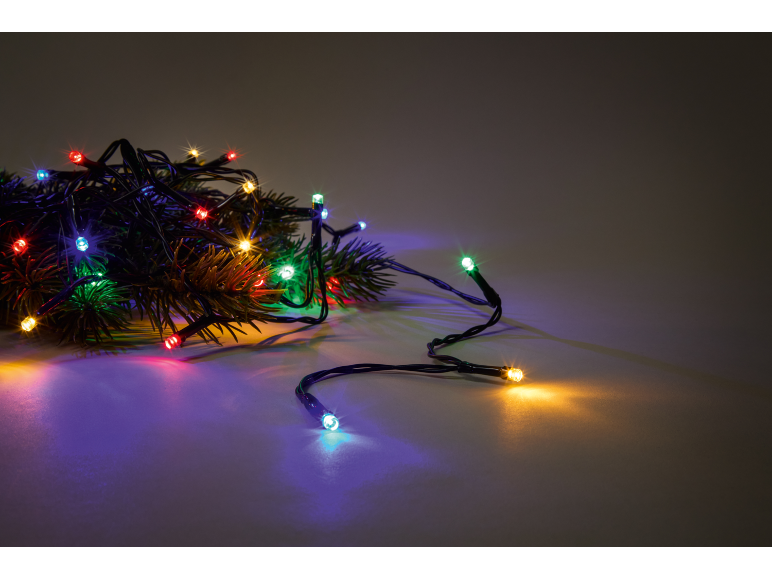 Guirlande lumineuse colorée sur des branches de sapin, créant une ambiance festive.