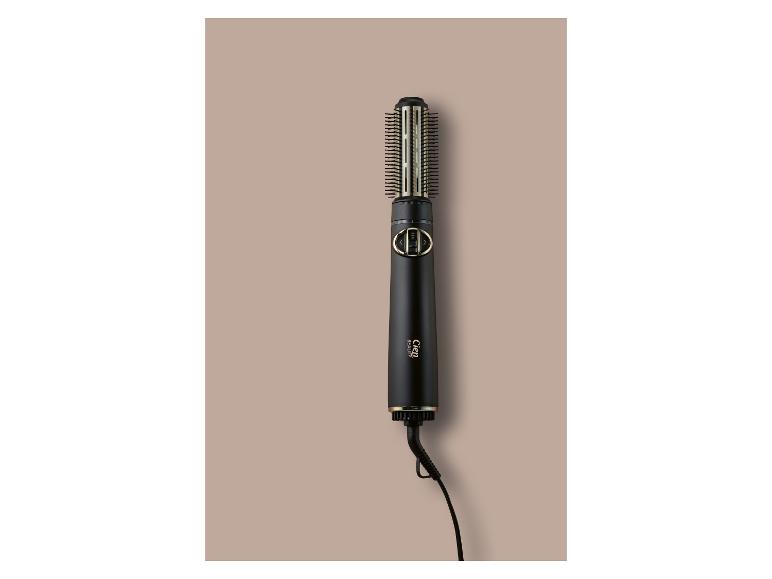 Brosse soufflante rotative noire avec des accents dorés et un cordon, sur fond beige.