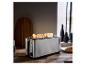 Long grille-pain en acier inoxydable avec toasts sur un comptoir en bois.