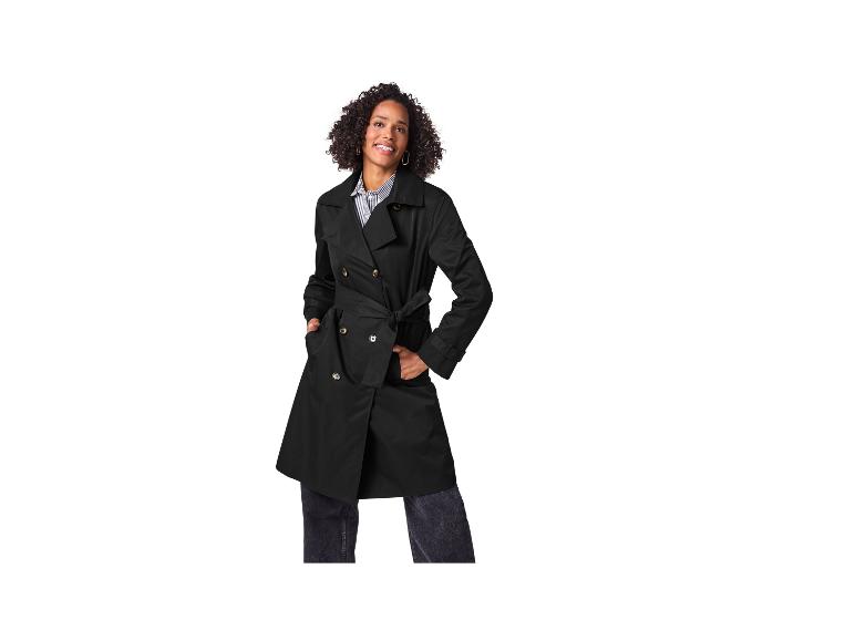 Femme souriante en trench-coat noir et chemise rayée.