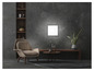 Un fauteuil moderne, une table basse et une plante dans une pièce sombre avec un luminaire mural clair.