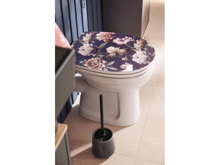 Toilettes avec abattant floral et brosse WC dans une salle de bain moderne.