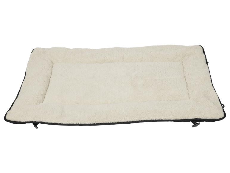 Un lit pour chien beige avec un bord noir et une fermeture éclair.