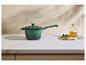 Casserole verte sur un comptoir avec une bouteille d'huile et du persil.