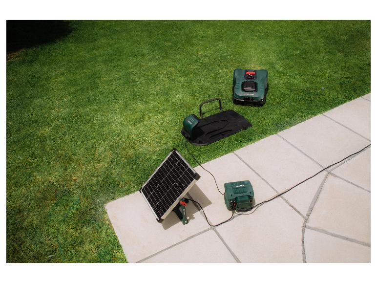 Tondeuse robot et station de charge avec panneau solaire sur pelouse et patio.