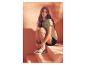 Femme en t-shirt vert clair et short noir assise sur des marches et portant des sandales beige clair.