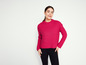 Une femme portant un pull rose et un pantalon noir.