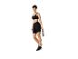 Femme en tenue de sport noire avec un bandeau, un soutien-gorge de sport, un short cycliste et une bouteille d'eau.