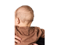 Bébé de dos, portant un sweat-shirt marron, tenu par un adulte.