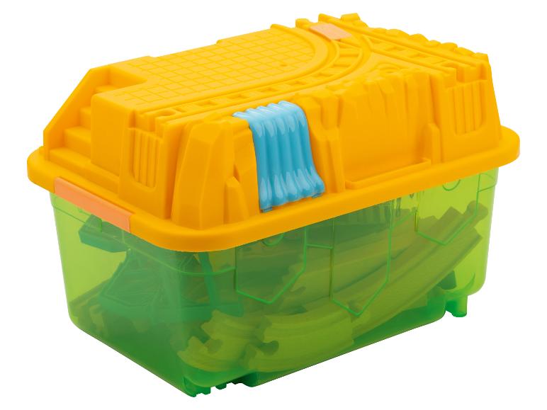 Boîte de rangement jaune et verte avec des pièces de train jouet.