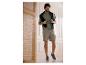 Homme en t-shirt vert, short cargo beige et baskets grises, souriant à l'intérieur.