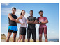 Quatre personnes en tenue de sport posent devant un ciel bleu.