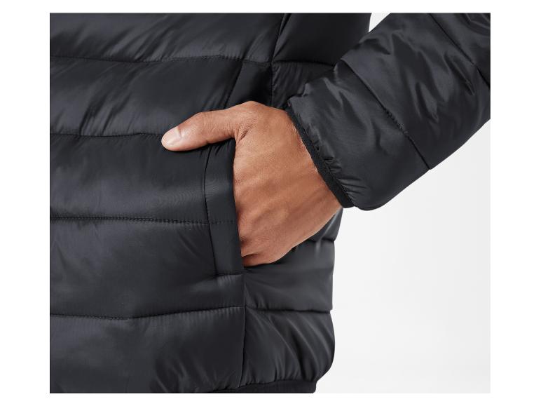 Gros plan sur une veste matelassée noire avec une main dans la poche.