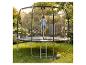 Enfant sautant sur un trampoline de jardin avec filet de sécurité, avec ballon et chaussures sur l'herbe.