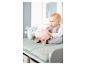 Un bébé assis sur une table à langer avec deux peluches, une rose et une bleue.