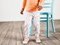 Un enfant portant un t-shirt rose et un pantalon blanc à cœurs.