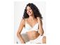 Femme en soutien-gorge et culotte blancs, assise et souriante.